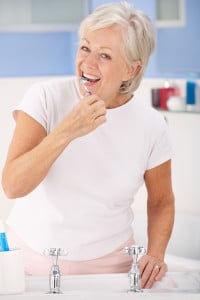 Pretty Senior Woman Brushing Her Teeth Over a Sink